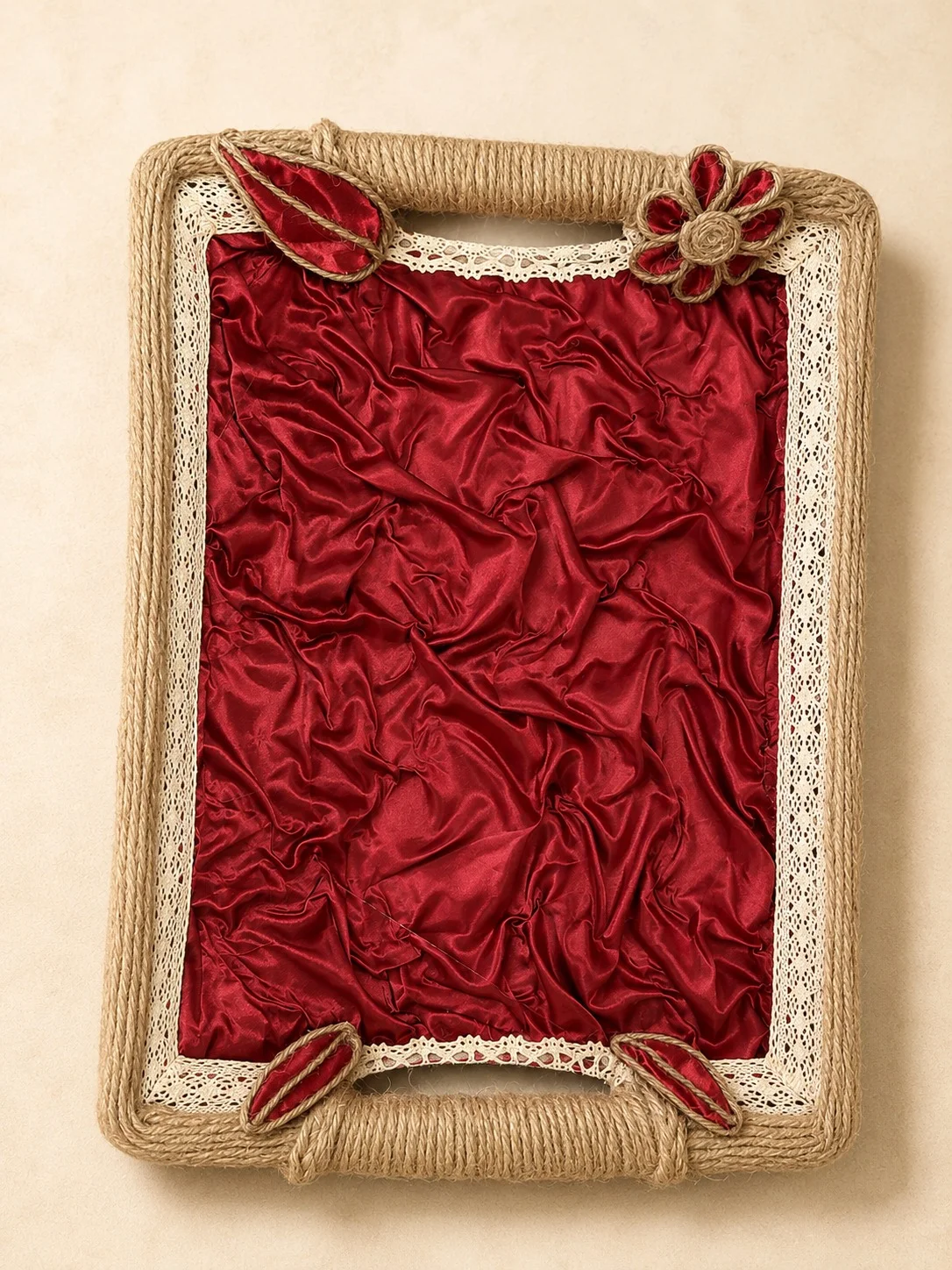 Rectangular tray with gathered crimson fabric, cream lace trim, twine-wrapped edges and handles, and red floral and leaf accents.