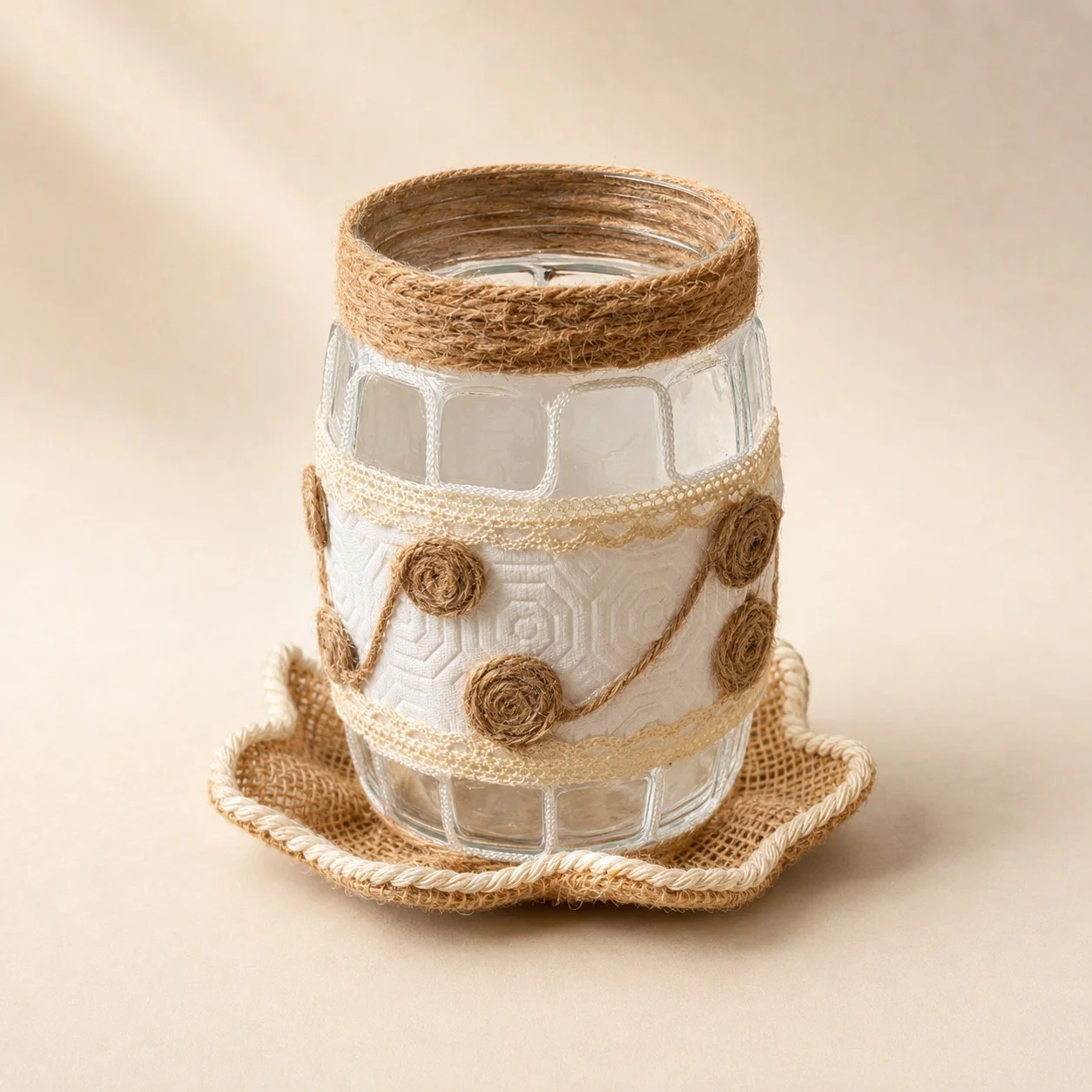 Clear jar with cream lace, white textured detailing, and twine rosettes, resting on a scalloped woven base.